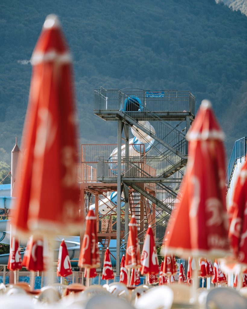 La torre degli scivoli di Aquaplanet Darfo Boario Terme vista tra gli ombrelloni rossi