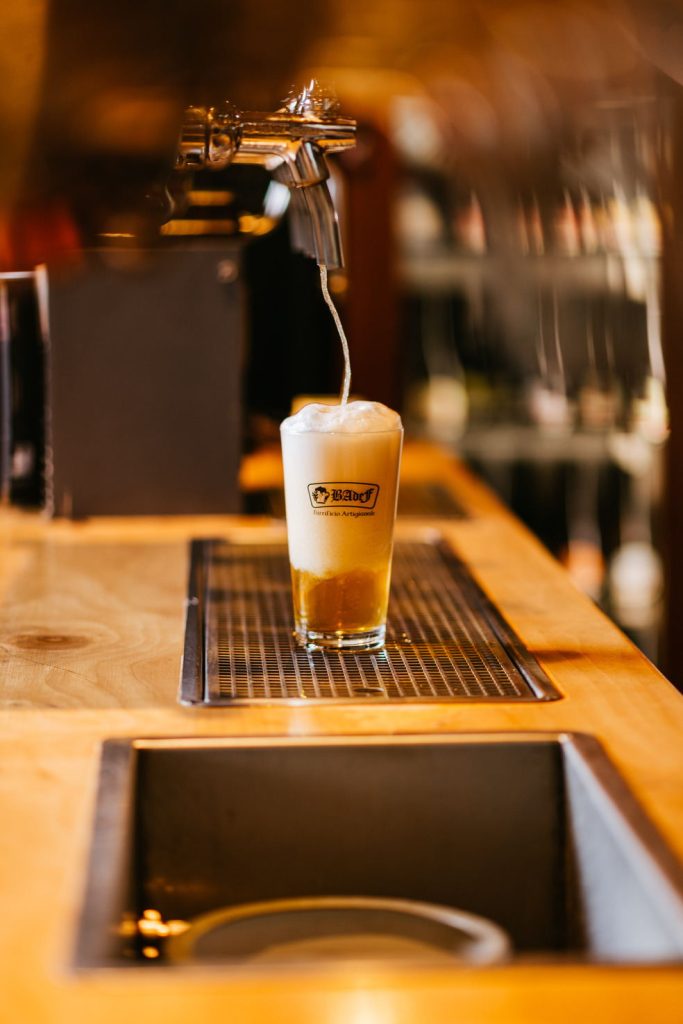 Birra Badef spillata in un bicchiere logato sul bancone del pub