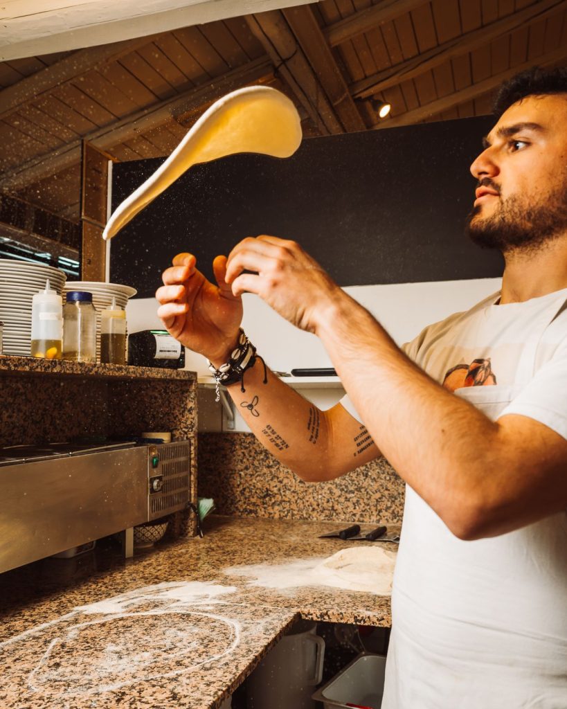 Il pizzaiolo stende limpasto della pizza