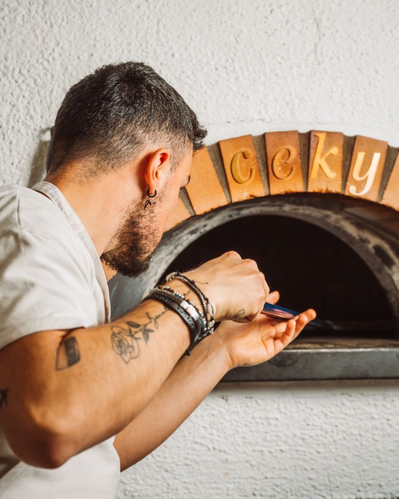 Il pizzaiolo infila la pizza nel forno a legna