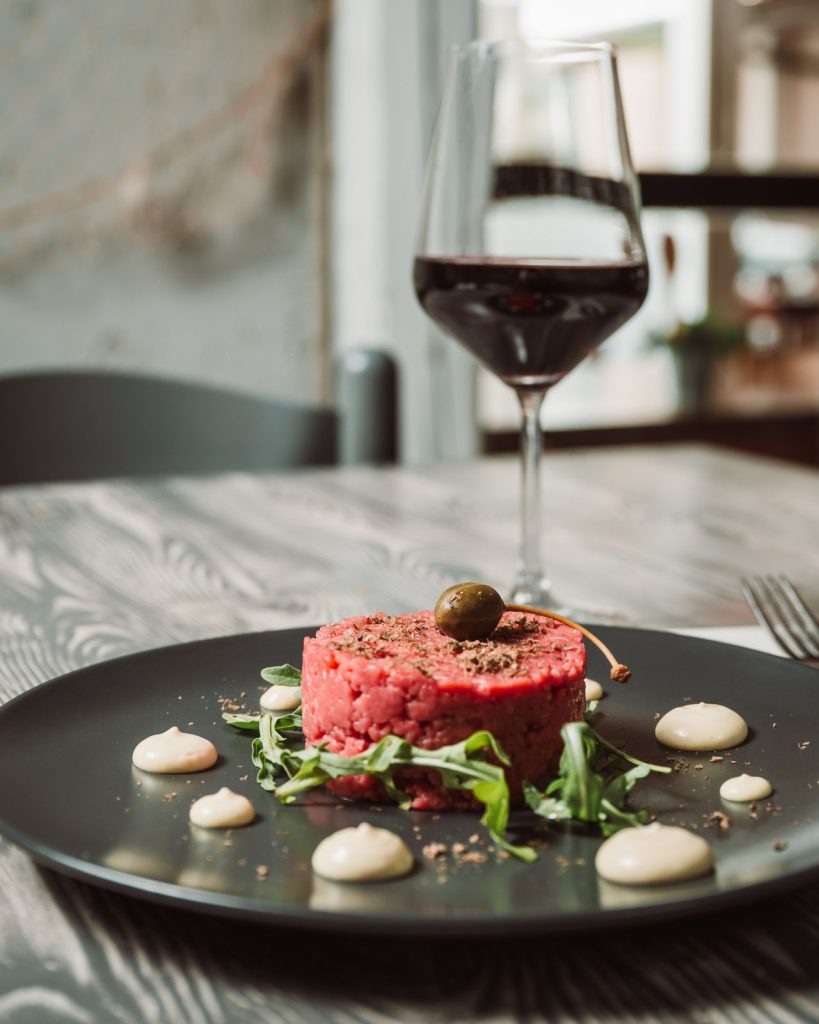 Tartare di carne impiattata con il bicchiere di vino rosso