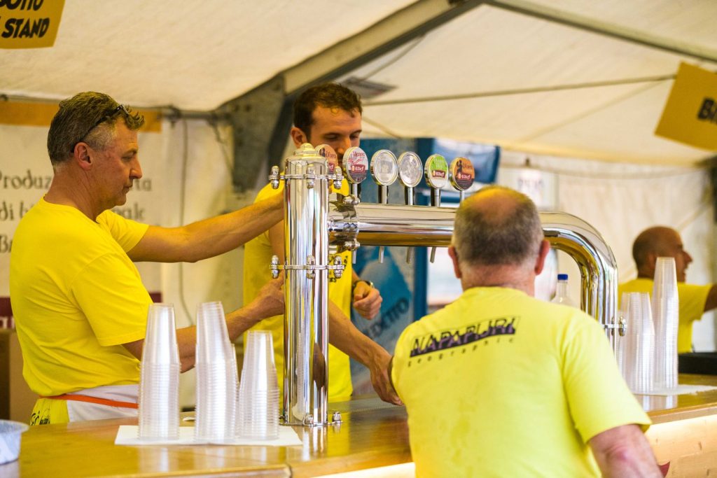 I volontari spillano la birra al banco della festa