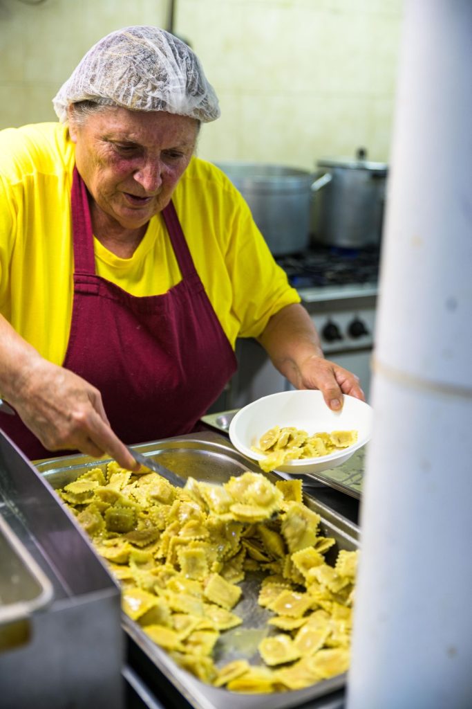 Una volontaria serve i casoncelli dal vassoio