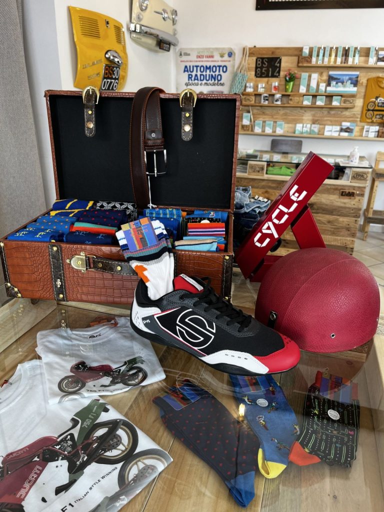 Accessori, caschi e borse esposti su un tavolo del negozio FuoriGiri Fashion