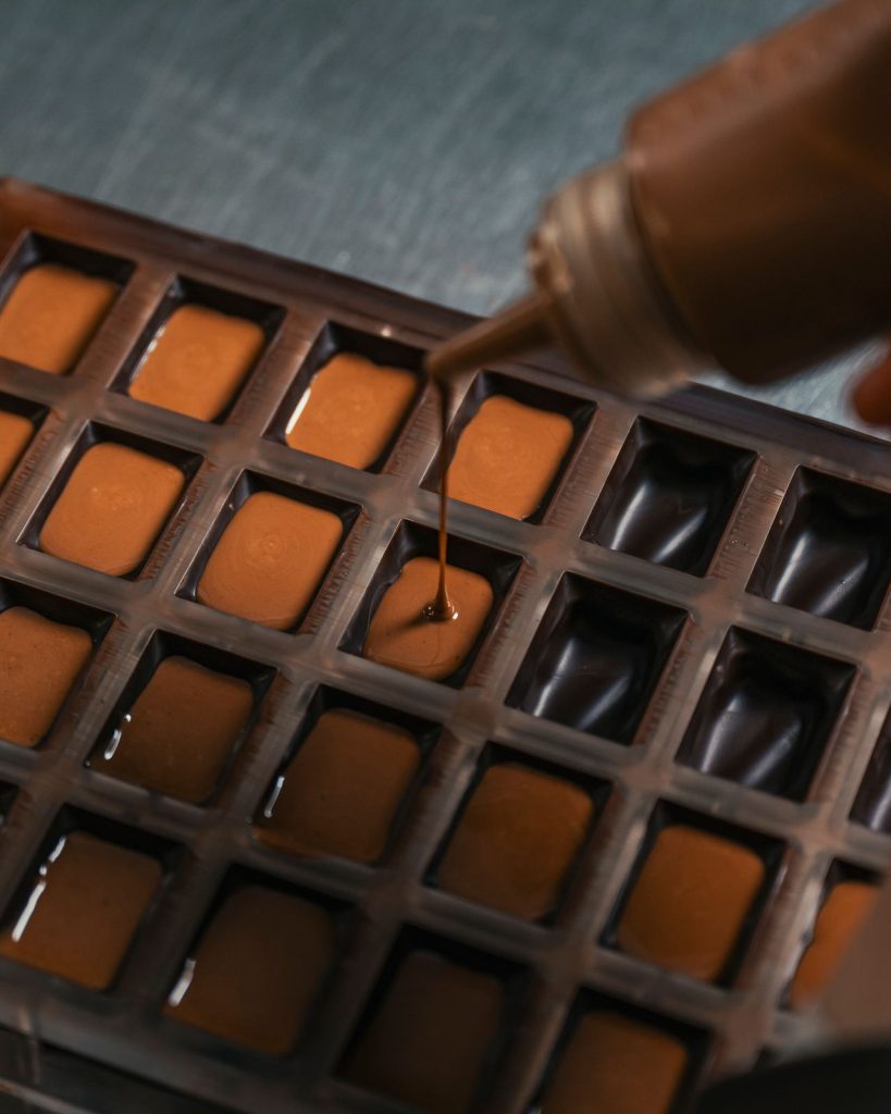 Cioccolato fuso colato dentro gli stampi dei cioccolatini