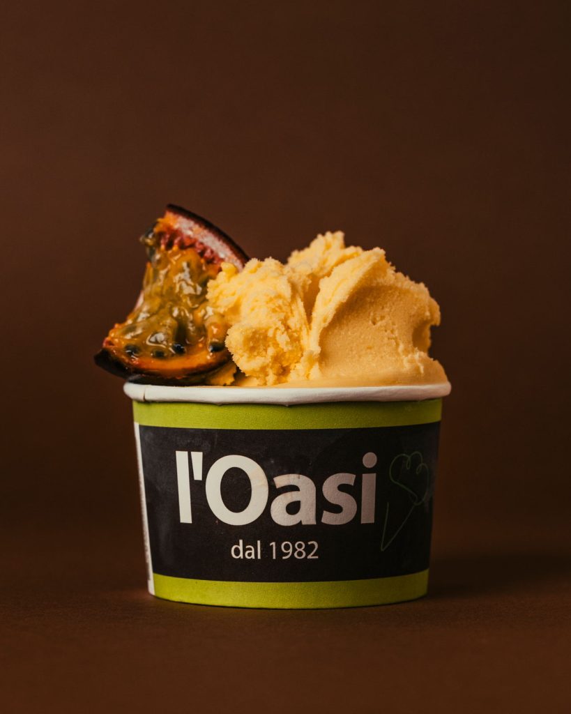 Coppetta di gelato al frutto della passione su fondo marrone