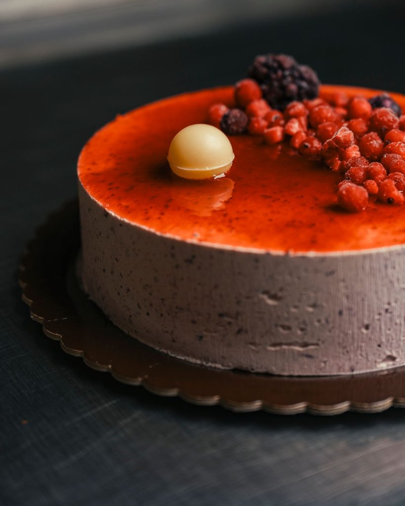 Torta gelato ai frutti di bosco con copertura rossa e frutta fresca sopra