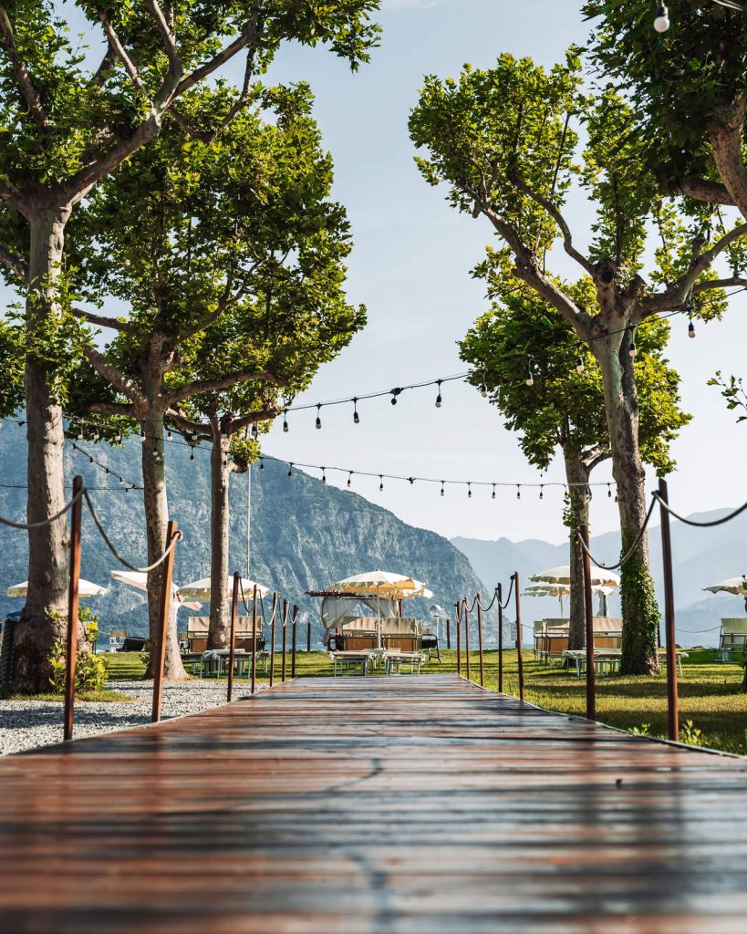 Passerella in legno del Lido Iseo con luci sospese tra gli alberi