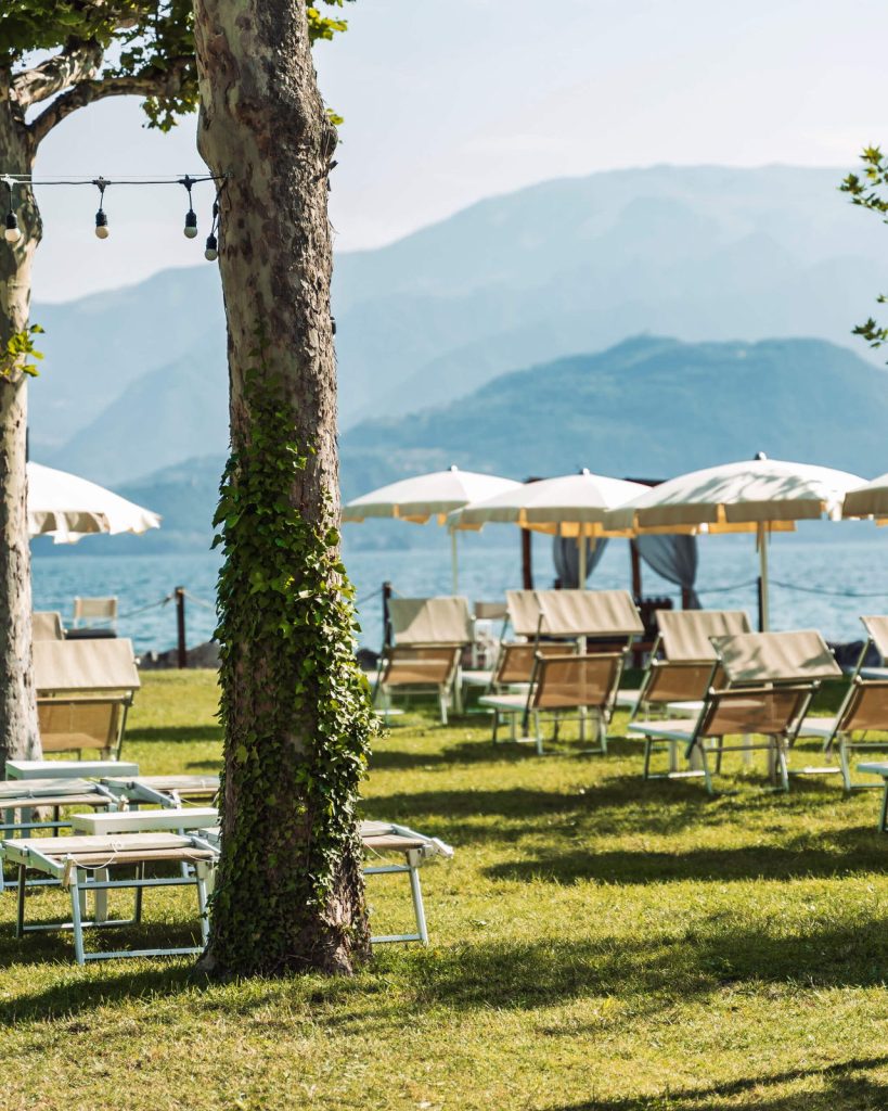 Prato alberato del Lido Iseo con lettini e ombrelloni vista lago