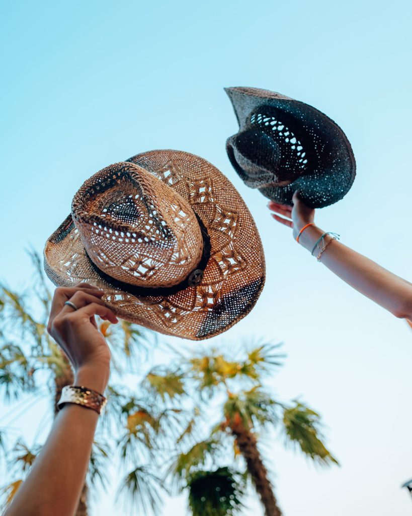 Cappelli da cowboy alzati verso il cielo fra le palme