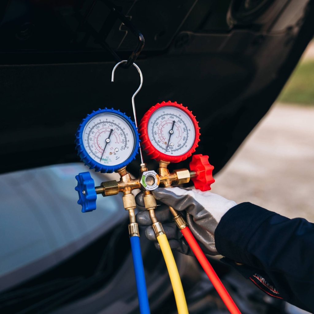 Manometri per la ricarica del climatizzatore collegati al motore di un'auto