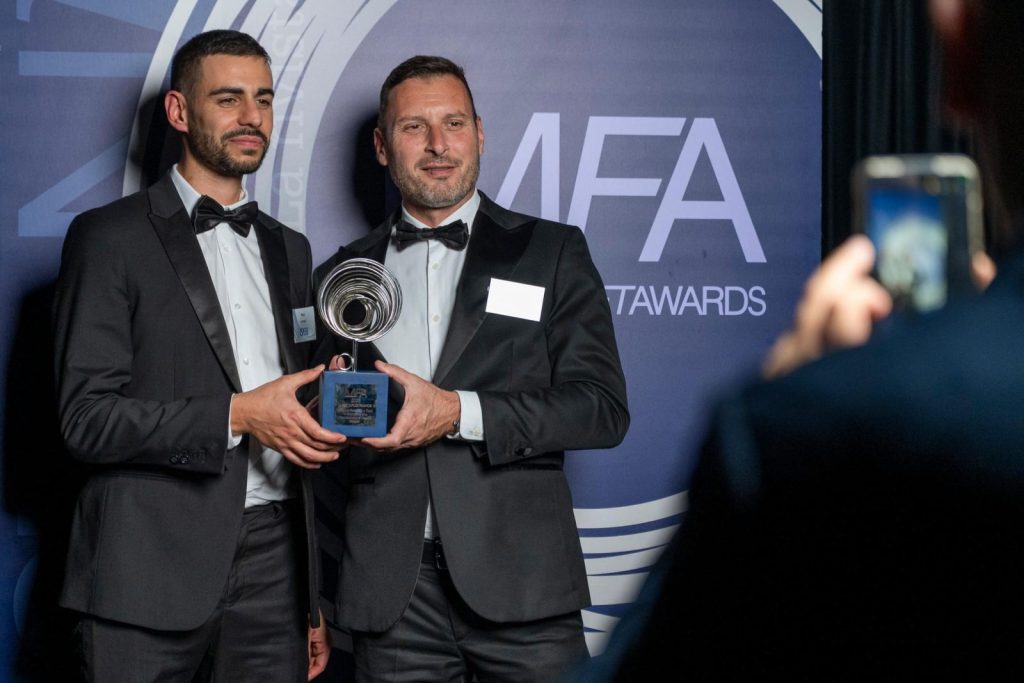 Due premiati con il trofeo sul palco di un evento Newsteca