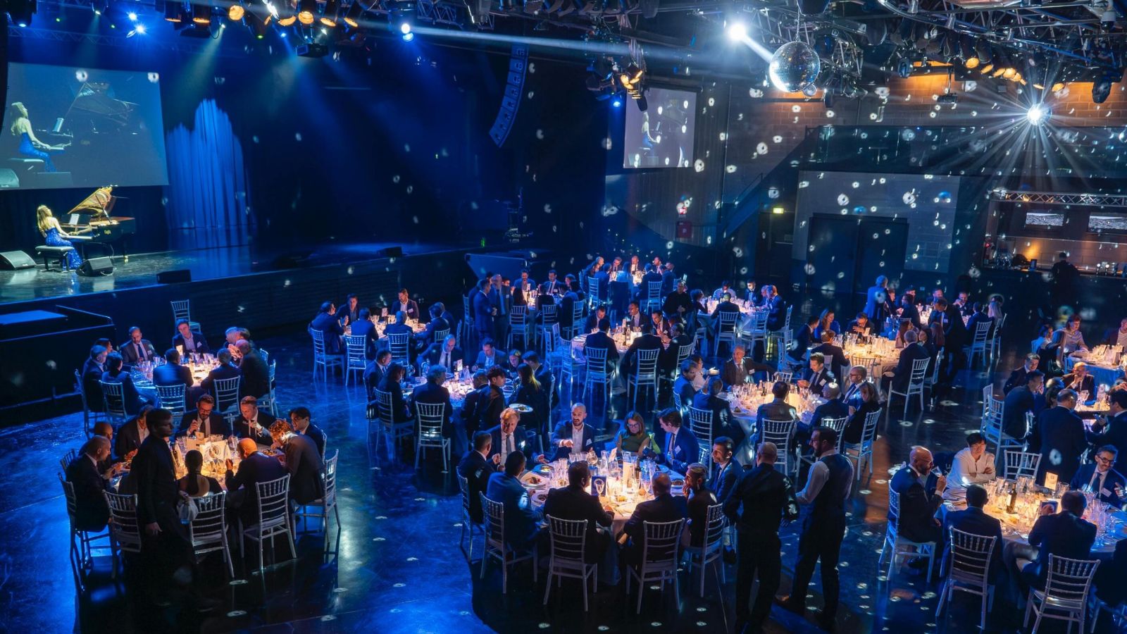 La sala della serata di gala Newsteca vista dall'alto, con i tavoli illuminati di blu