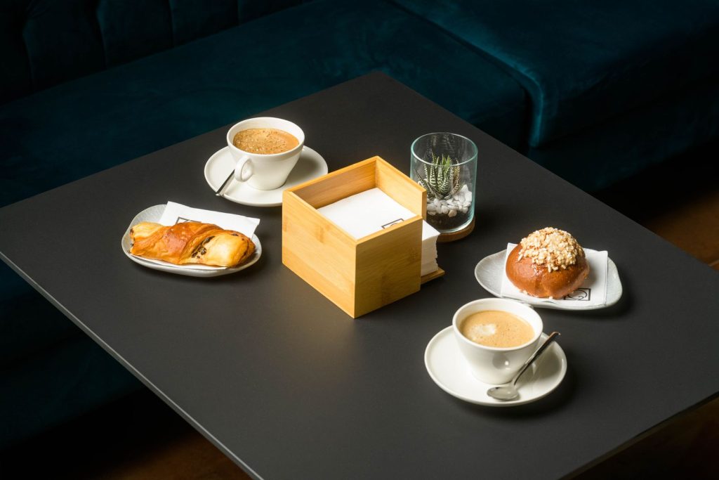 Due cappuccini e una brioche serviti sul tavolo per la colazione