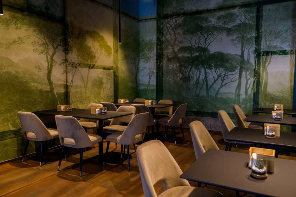 La sala interna con il murale di alberi e i tavoli apparecchiati