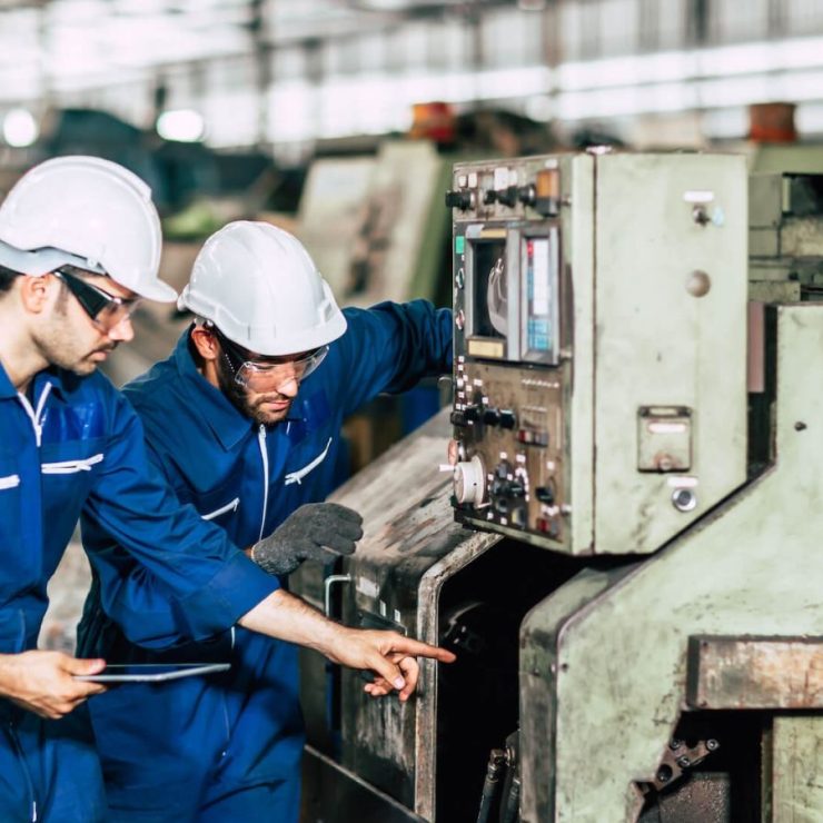 Due addetti di SNG Multiservice al lavoro su un macchinario in un capannone industriale