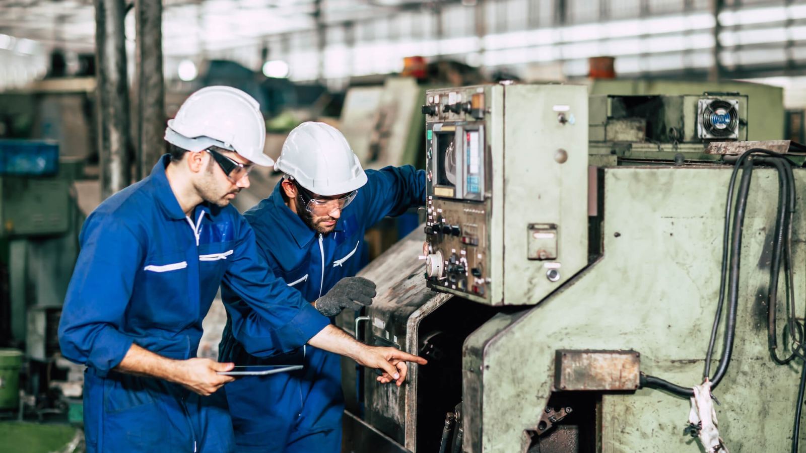 Due addetti di SNG Multiservice al lavoro su un macchinario in un capannone industriale