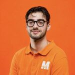 Gabriele Spada, co-fondatore di MakeItWeb, sorridente in polo arancione