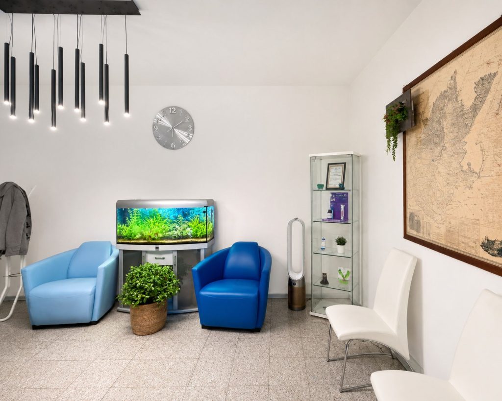 La sala d'attesa con le poltroncine azzurre, l'acquario e una mappa antica alla parete