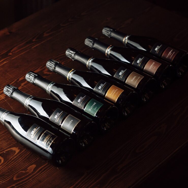 Le bottiglie di Franciacorta di Tenuta Ambrosini fotografate su un tavolo in legno
