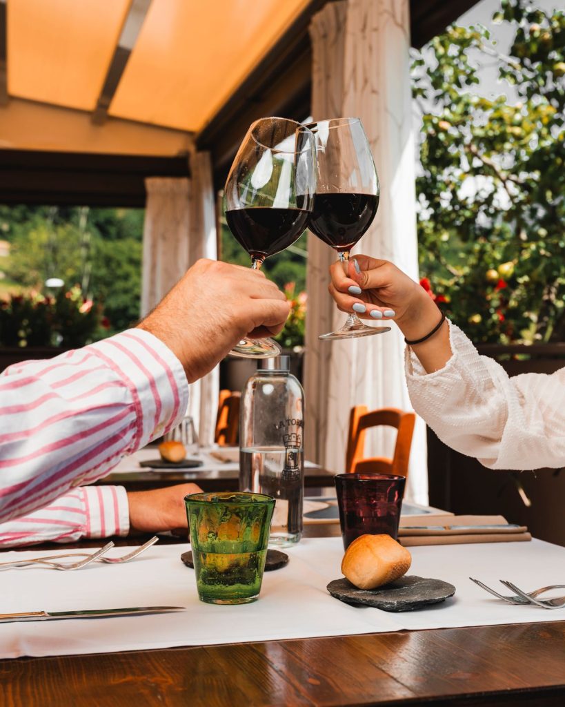 Due ospiti brindano con il vino rosso nella veranda del Ristorante La Torre di Zogno