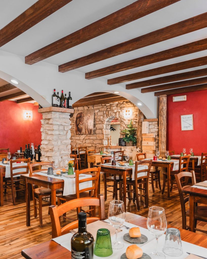 La sala interna del Ristorante La Torre di Zogno con le pareti rosse, la pietra a vista e le travi in legno