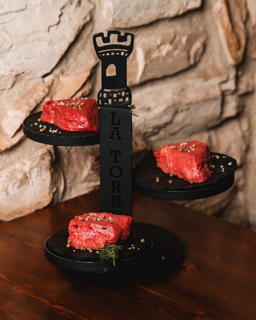 Tre tagli di manzo crudi sull'alzata nera a forma di torre del Ristorante La Torre di Zogno
