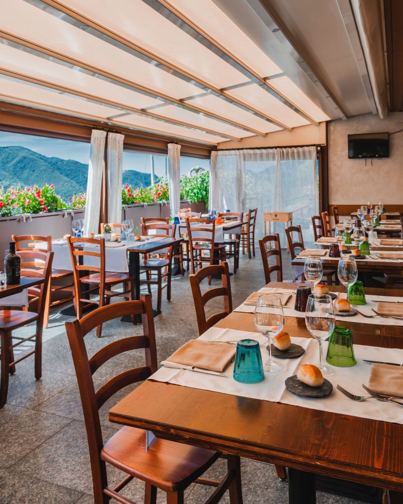 La veranda del Ristorante La Torre a Zogno con i tavoli apparecchiati e le montagne della Val Brembana